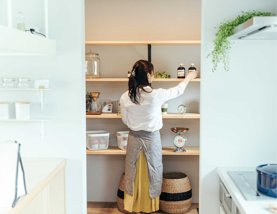 壁面の棚に物を片付ける女性