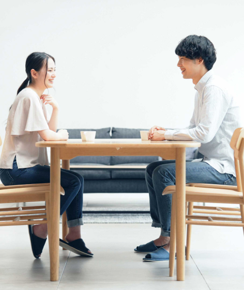 ダイニングテーブルで向かい合って話すご夫婦
