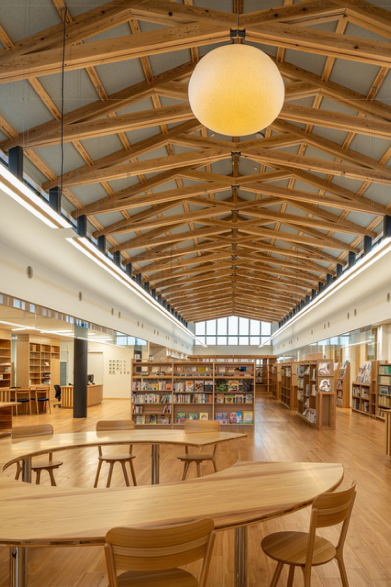 木の梁が架かる明るい図書館の内観