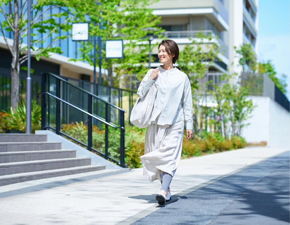 緑のある街並みを歩く女性